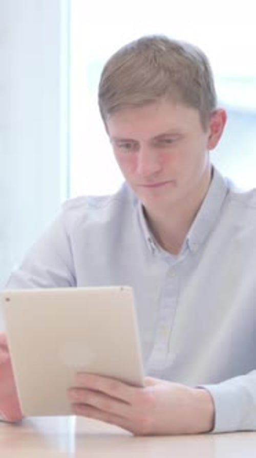 Upset Man Using Tablet Indoors in Natural Light