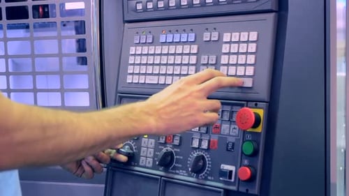 Man working on the control panel works with an industrial machine at the factory close-up.
