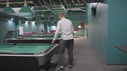 Back Shot of Player Touching Green Pool Table in Modern Billiard Room