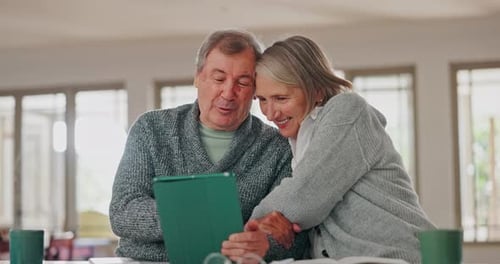 Happy Senior Couple Looking at Tablet at Home
