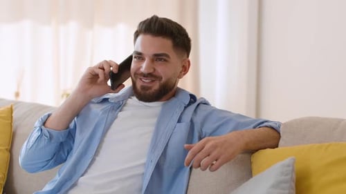 Man Relaxing on Couch While Talking on Phone