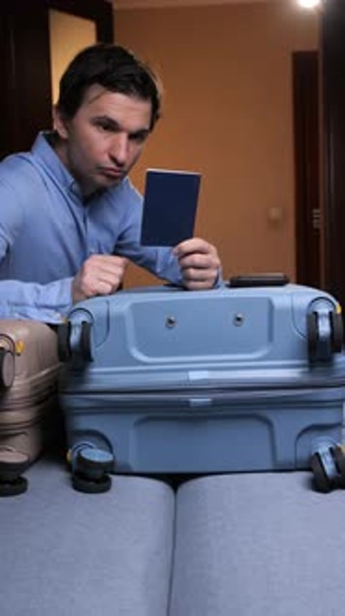 Man Checks Passport Before Travel with Luggage at Home