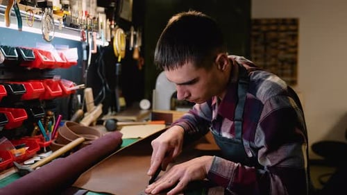 Focused Artisan Cutting Leather in a WellEquipped Workshop