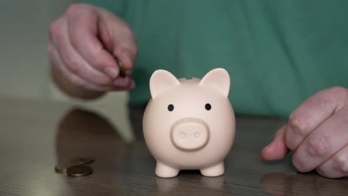 Man saving money putting coins in piggy bank