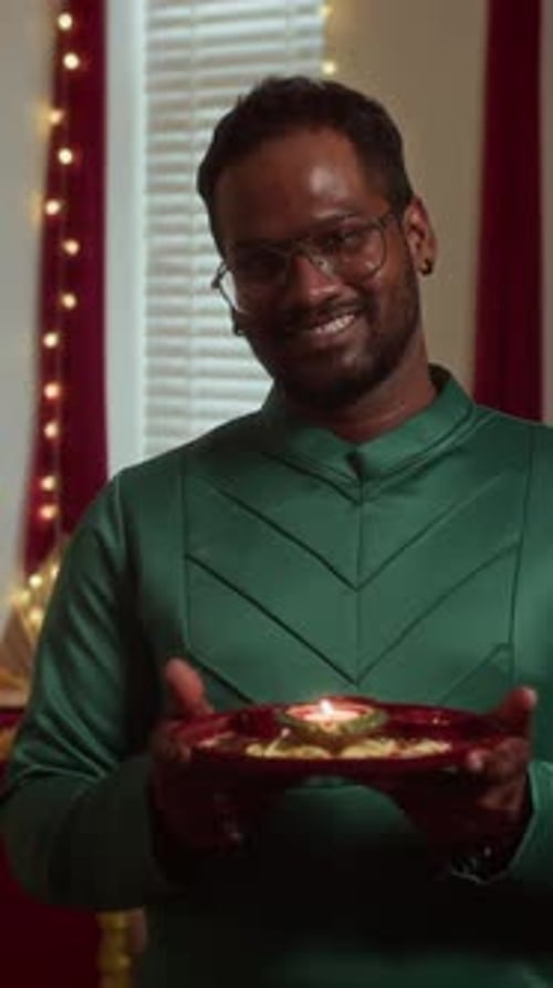 Man Smiling Holding Lit Candle on Decorative Plate