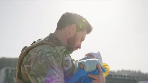 Soldier Cradles Baby Wearing Flag Colors