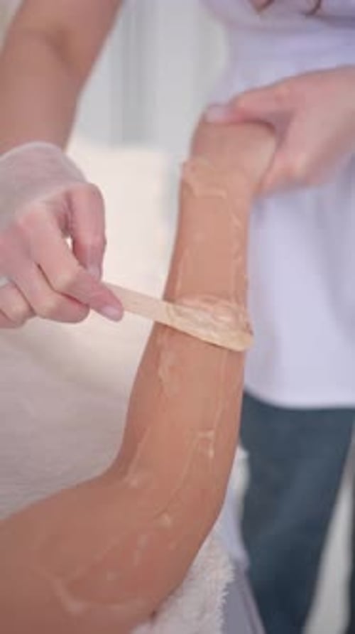 Beautician Applying Wax to Client Arm