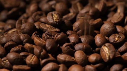 Slow motion of roasted coffee beans falling.