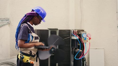 Worker Uses Laptop to Repair Air Conditioning Unit