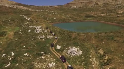Luftaufnahme von Geländewagen neben einem See in the Field an einem sonnigen Tag im Sommer. abseits der Straße