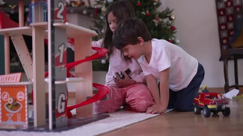 Kids Playing with Toy Car Garage by Christmas Tree