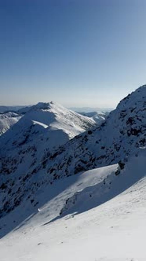 Vídeo vertical: vista de la estación de esquí de las montañas cubiertas de nieve y el campo en un día soleado