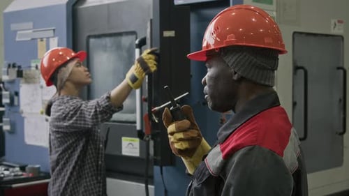 Factory Technician Giving Orders to Workmen via Walkie-Talkie