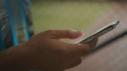 A Man Standing on the Street in the Evening Holding a Cell Phone in His Hand Using an App