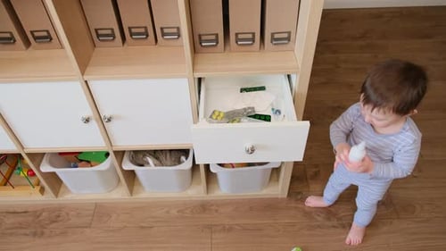 Child Playing with Toys in Cabinet Drawer