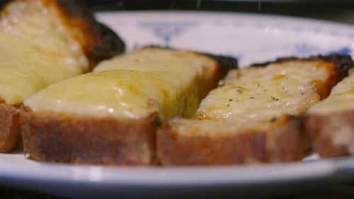 Pfeffergranulat, das in Zeitlupe auf geschmolzenen Käse auf hausgemachtem Toast fällt.