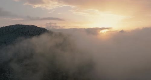 Flying Through the Clouds Close to the Mountains at Sunset