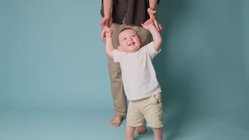 Happy toddler baby learns to walk and takes his first steps with the help mother