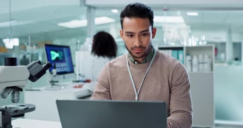 Focused Young Adult Scientist Works on Laptop in Lab