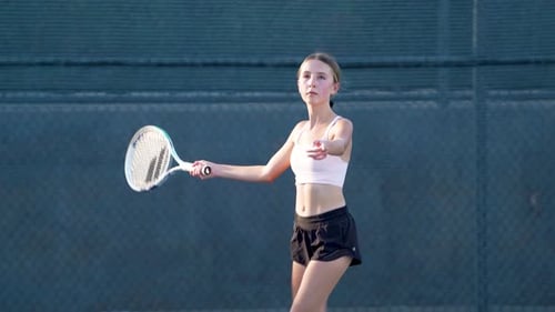 Teen Girl Serving Tennis Ball on Outdoor Court