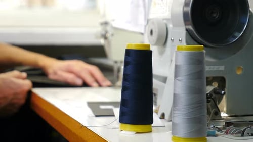 Un designer coud du tissu dans un atelier de couture