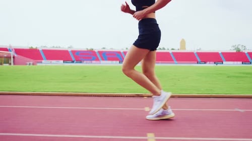 Close up of sportswoman sprint on a running track outdoors on stadium.