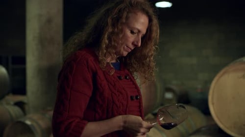 Woman smelling aromatic tuscan wine sampled from barrel in italy's winery cellar