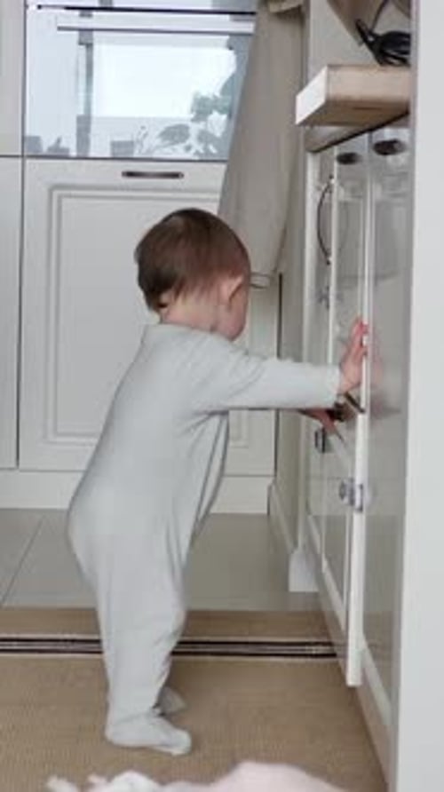 Young Child Opens Cabinet in Bright Home Kitchen