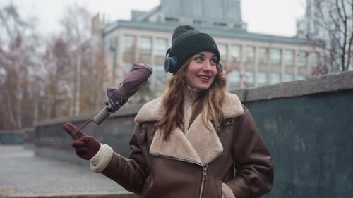 Woman in Shearling Jacket Playfully Swinging Umbrella on Autumn Street