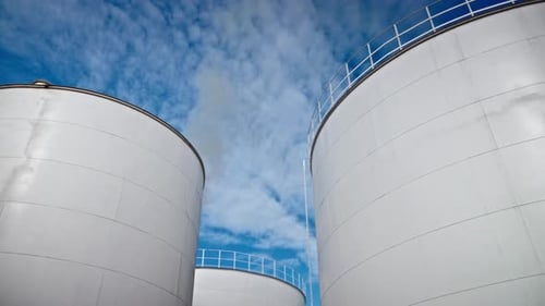 Large Industrial Tanks Against Blue Cloudy Sky