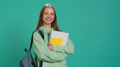 Portrait of Jolly Pupil with School Supplies in Arms