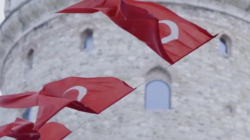 Flags Blowing Near Ancient Stone Tower