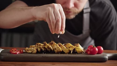 Professional Chef serving chicken breast with salt, meat grill steak with spices
