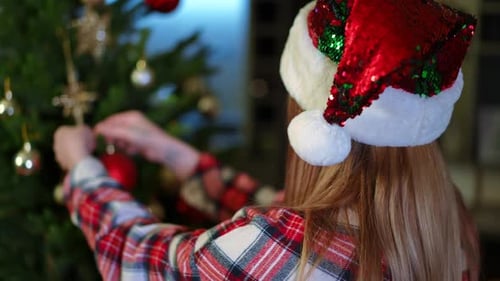 Woman Decorating Christmas Tree in Santa Hat