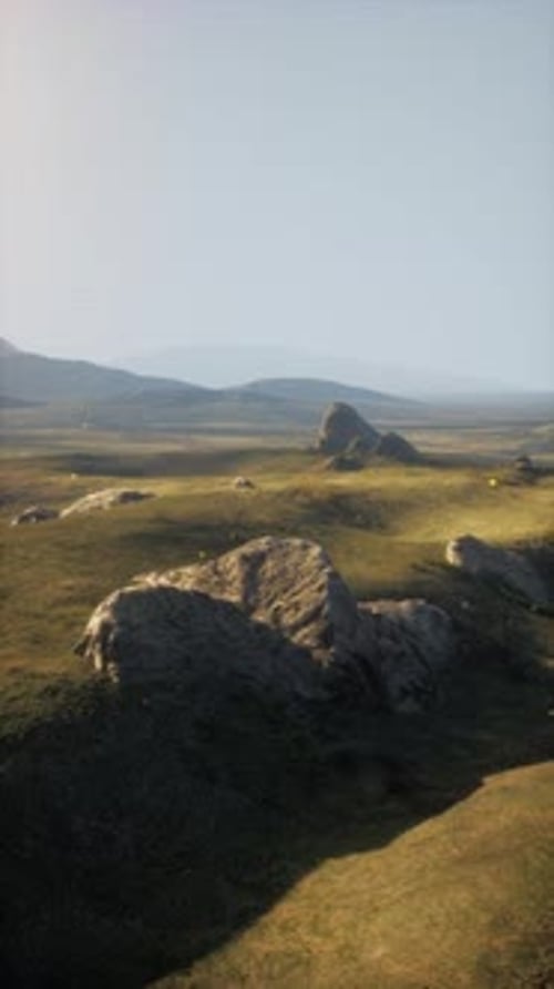 Grassy Field With Rocks and Mountains