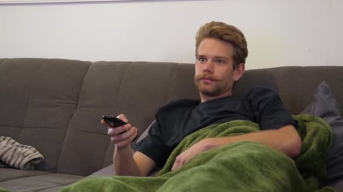 Man Relaxing on Couch with Television Remote