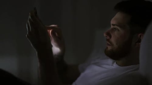 Young Man Uses Tablet in Bed at Night