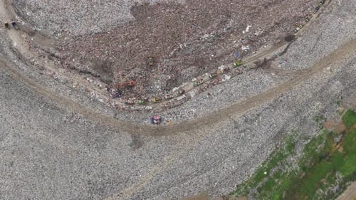 Aerial view of garbage trucks dumping waste in a bali landfill