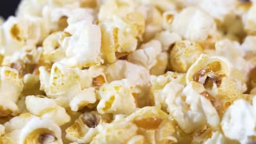 Gros plan de Popcorn tournant sur une plaque tournante. Une collation légère à emporter au cinéma.
