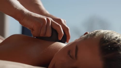 Close Up of a Relaxing Hot Stone Massage on a Woman Back in a Peaceful Spa Setting Highlighting