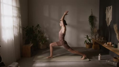 Young Yogini Doing Warrior Asana Sequence while Training at Home