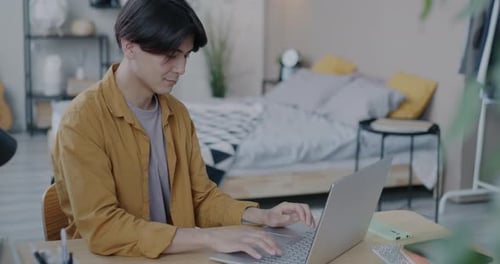 Young Adult Works on Laptop at Home