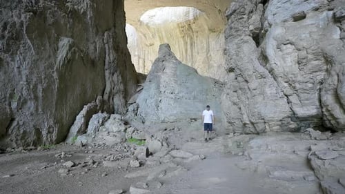 Man Walking Inside The Prohodna Cave With The Eyes of God Formation In Iskar Gorge, Karlukovo,