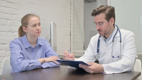 Male Doctor Talking with Female Patient in Clinic