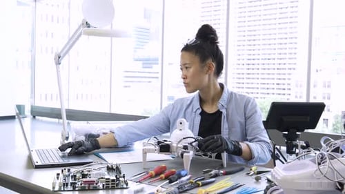 Female scientist assembling robotics at laptop in a modern science laboratory