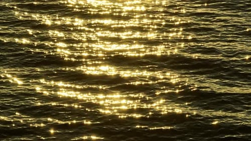 Das Meer schimmert mit goldenen Reflexen unter der Sonne.