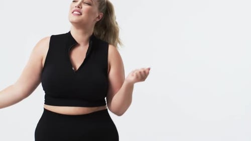 Caucasian plus size woman with blonde hair in ponytail dancing in studio, copy space