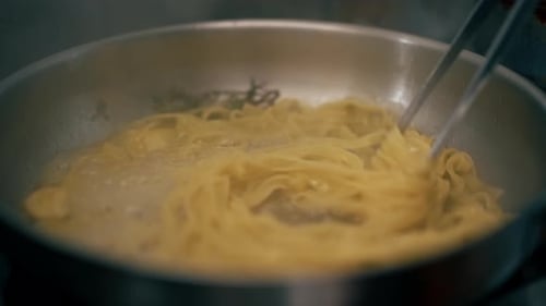 Pasta being cooked and stirred in pan