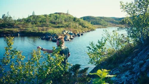 Norwegian Guy With Fishing Rod Catching Fish On A Calm Lake. Static Shot