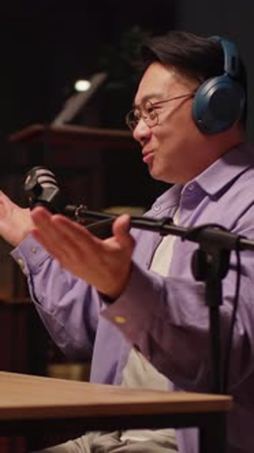 Close Up Asian Content Creator Man Talking on Podcast on Laptop with Headphones and Microphone